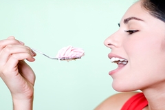 Image Woman eating teaspoonful of sweet